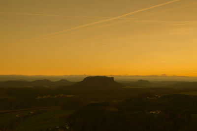 Scenic view of silhouette landscape against orange sky