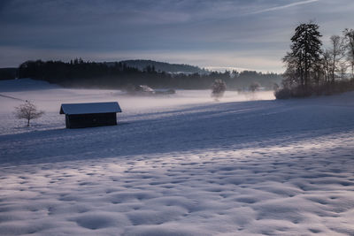 Scenic view of snow covered field against sky