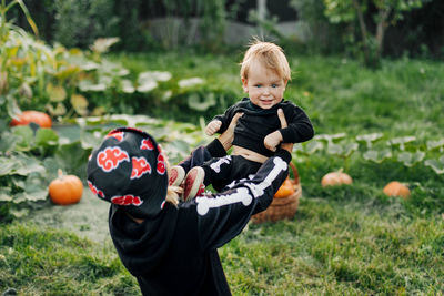 The older sister and her little brother in skeleton costumes, the girl throws the boy up. 