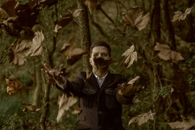 Man throwing autumn leaves in forest