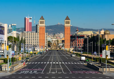 View of venetian towers in barcelona with empty street, moutains in the back and sunny day.