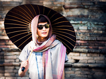 Portrait of young woman wearing sunglasses standing outdoors