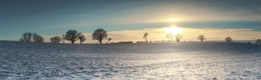 Scenic view of snow covered field against sky during sunset