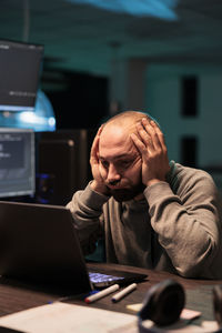 Side view of man using laptop at office