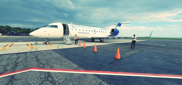 Airplane on airport runway against sky