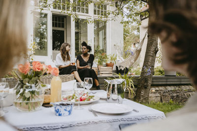 Young women with drinking glass talking while sitting in backyard