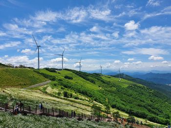 Wind turbines on field against sky