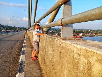 A small child is looking at the mahakam river from the crown bridge 2 in the afternoon