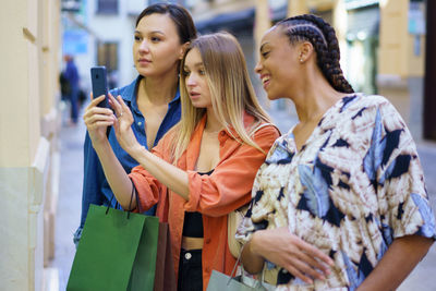 Woman photographing through smart phone while standing with friends