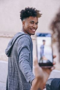 Woman photographing boyfriend standing at home