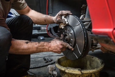 Midsection of mechanic repairing car in garage