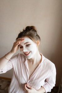 Young woman looking away against wall