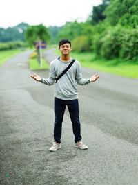 Full length portrait of young man standing on road