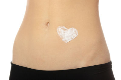 Close-up of woman holding heart shape over white background