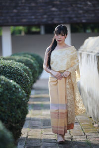 Full length portrait of young woman walking on footpath