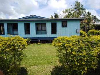 View of house and plants on field against cloudy sky