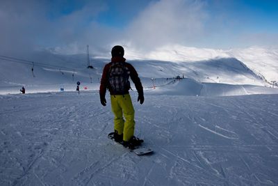 Rear view of man skiing on snow covered landscape