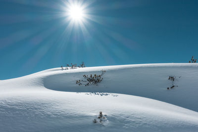 People on frozen field against clear sky during sunny day