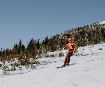 Female in red skis down baldface mountain, nh on a cold morning.