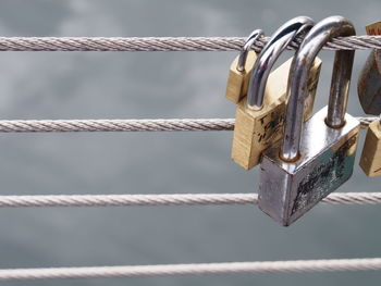 Close-up of love locks hanging on metal rope