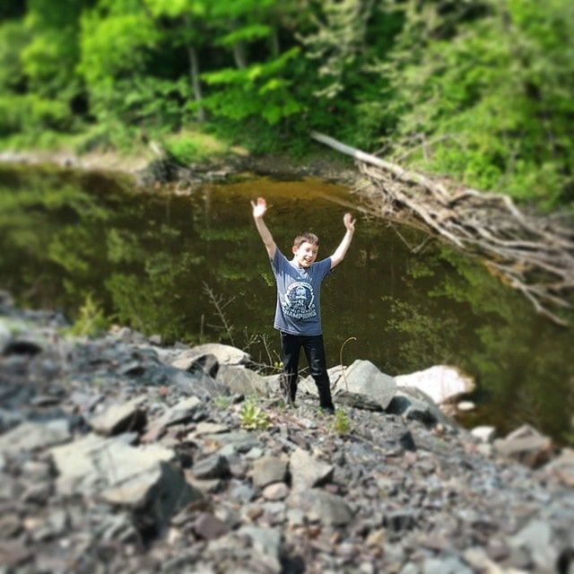 full length, lifestyles, casual clothing, leisure activity, standing, rear view, forest, tree, young adult, nature, walking, front view, focus on foreground, day, person, outdoors, rock - object, arms outstretched