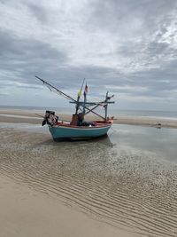 Fishing boat on beach against sky