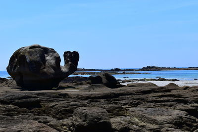 Rock formations on beach against clear blue sky