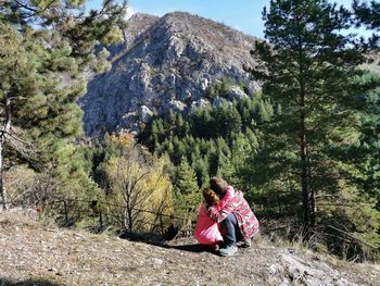 Girl and boy embracing while sitting on mountains