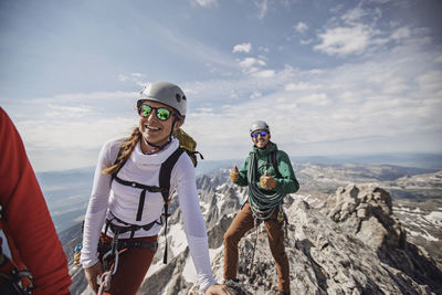 Three rock climbers smile after reaching the summit of the grand teton
