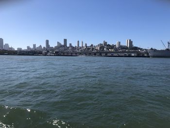Sea by buildings against clear sky