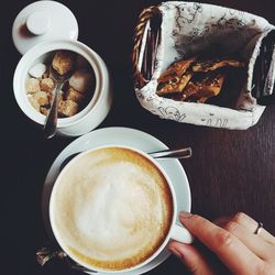 Close-up of hand holding coffee cup on table