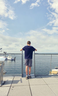 Rear view of man standing by sea against sky