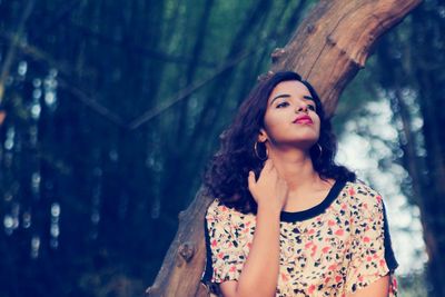 Woman looking away against tree