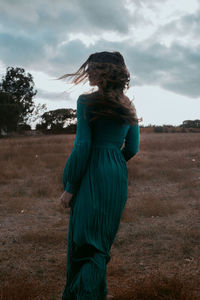 Midsection of woman standing on field against sky