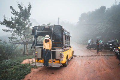 Rear view of people working on road against sky