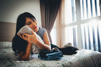 Smiling young woman lying on bed at home