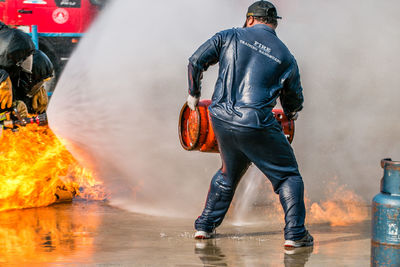 Rear view of firefighter holding cylinder