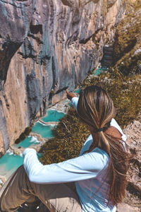 Rear view of man sitting on rock