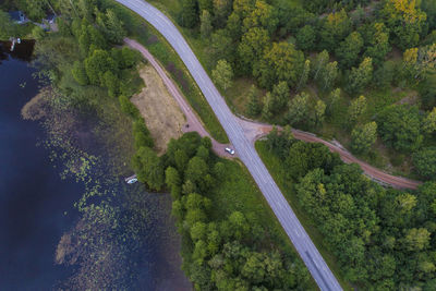 Aerial of a road by a lake and forest before sunset in summer