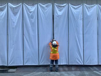 Rear view of boy standing against blue wall