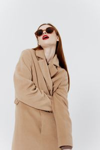 Portrait of young woman wearing sunglasses against white background