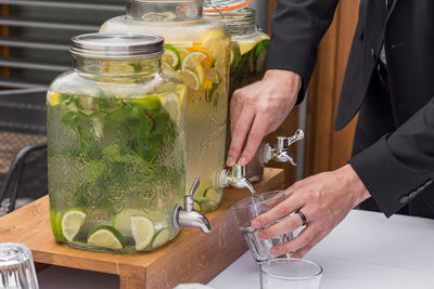 Man takes a glass of homemade citrus lemonade.