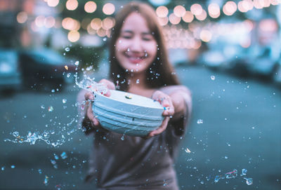 Portrait of smiling woman holding smart phone during winter