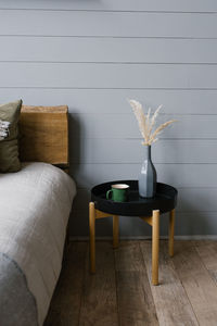 A vase of dried flowers and a mug on the scandinavian-style bedside table in the bedroom.