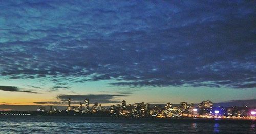 View of illuminated cityscape against cloudy sky