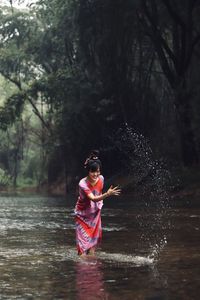 Happy woman splashing water in lake