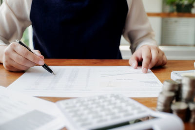 Midsection of man holding paper on table