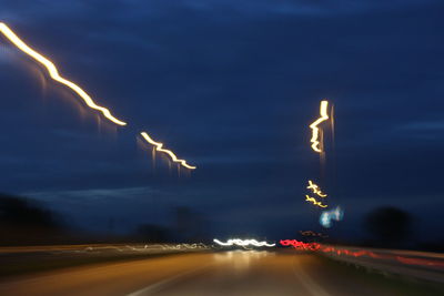 Light trails on road against sky at night