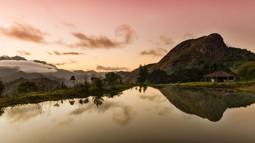 Scenic view of lake and mountains against sky at sunset