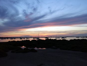 Scenic view of beach against dramatic sky during sunset